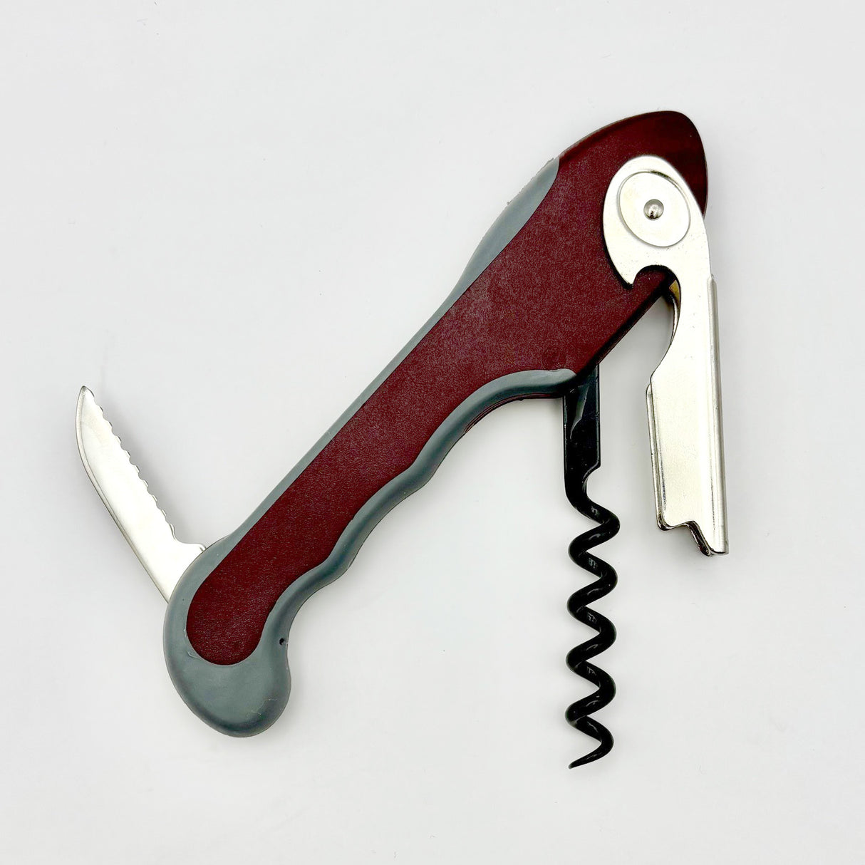 The Soft Touch 001 Single Lever Waiter's Friend Corkscrew by Soft Touch is a versatile wine opener with a red and gray handle, featuring a single lever corkscrew, a small serrated knife, and a bottle opener, all extended against a white background.