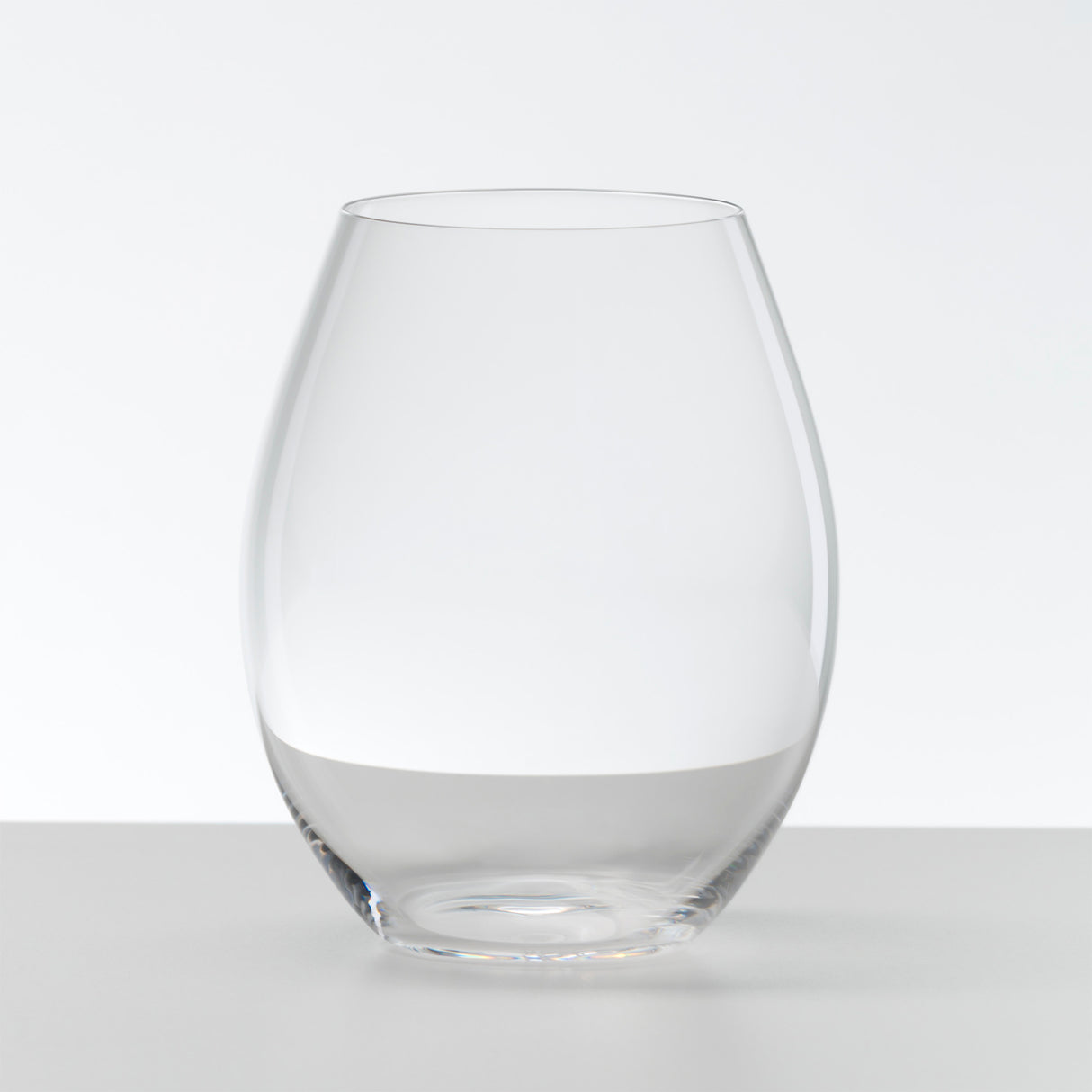 A set of two Riedel O Range Stemless Old World Syrah glasses (0414/41) sits elegantly on a white surface against a plain white background, highlighting their stylish form and easy-to-clean, dishwasher-friendly design.