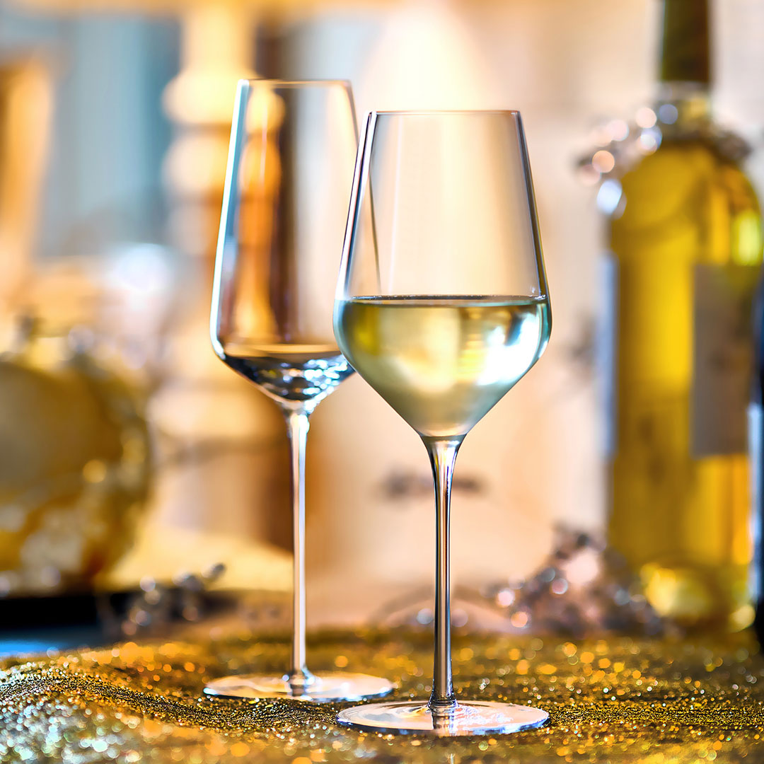 Two wine glasses with white wine on a festive table with blurred background