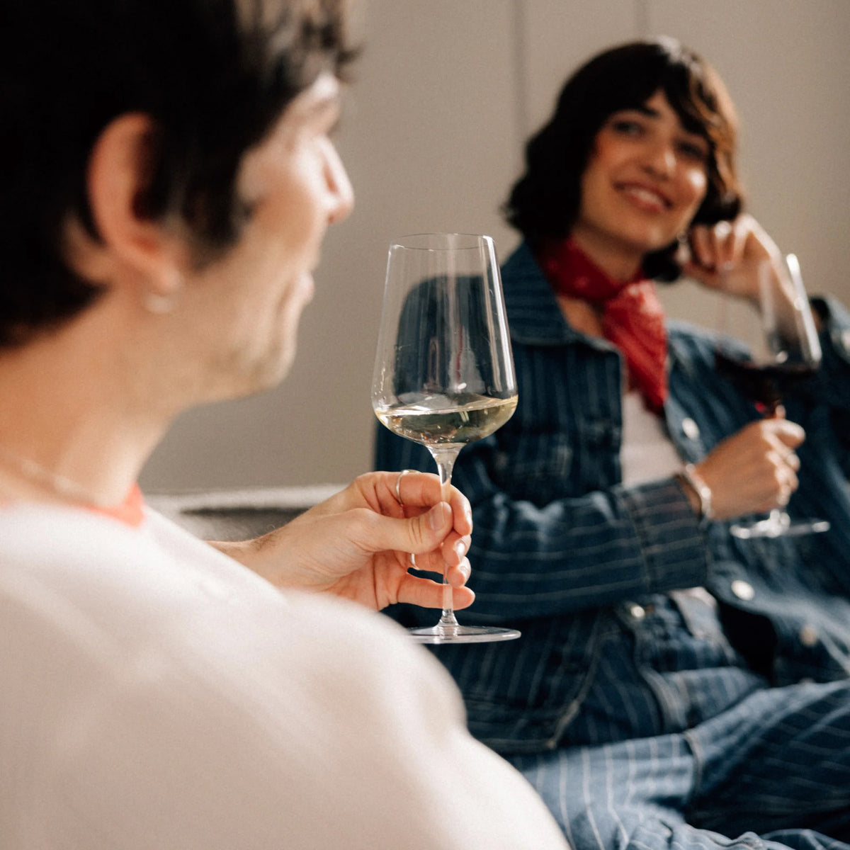 A man and a woman sit together looking at each other while holding Stolzle STARlight Universal Red & White Wine Glass crystal glasses.
