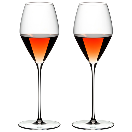A set of two clear crystal wine glasses filled with rose wine, showcasing a tall stem and a thin bowl.