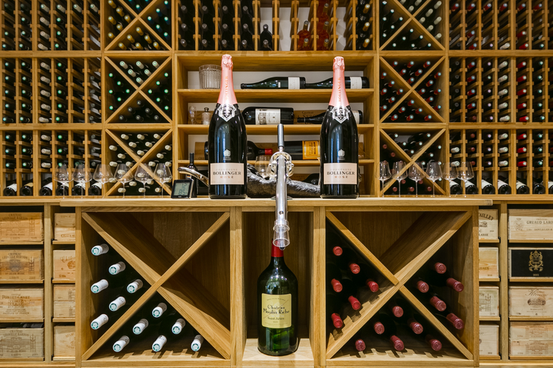 A collection of different wooden wine racking methods, full with different bottles.