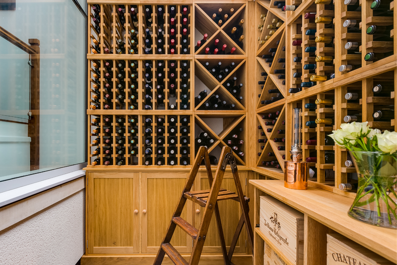 A collection of different wooden wine racking methods, full with different bottles.