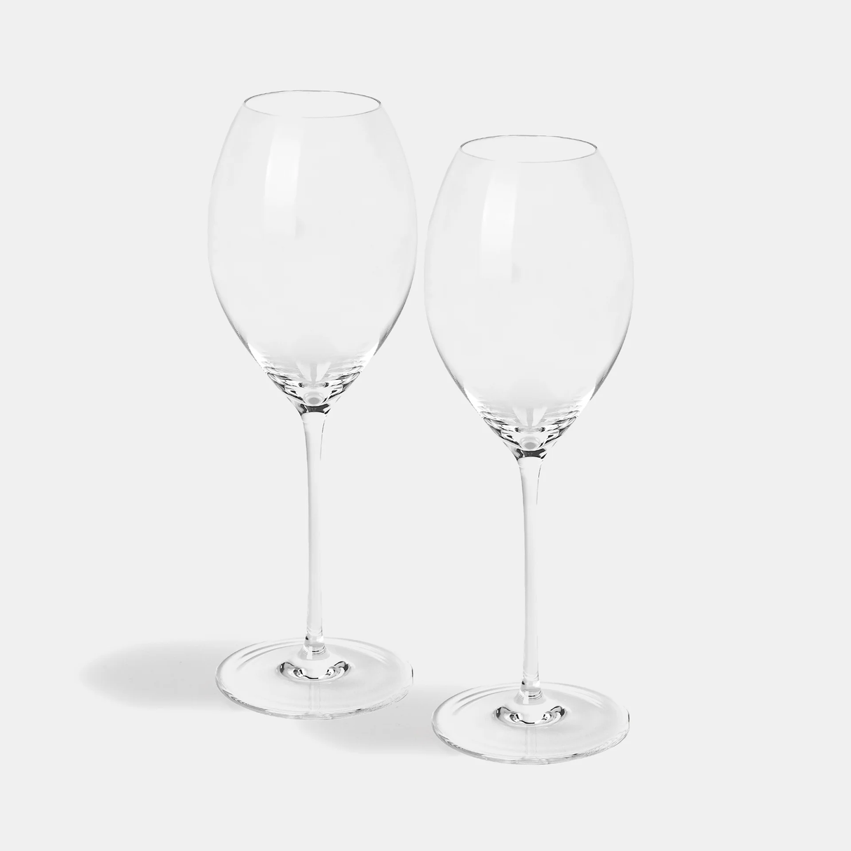 A pair of Jancis Robinson x Richard Brendon The Occasional Collection Champagne/Sparkling Wine Glasses sit side by side on a light gray background, their long stems and clear design casting soft shadows below. Set includes two glasses.