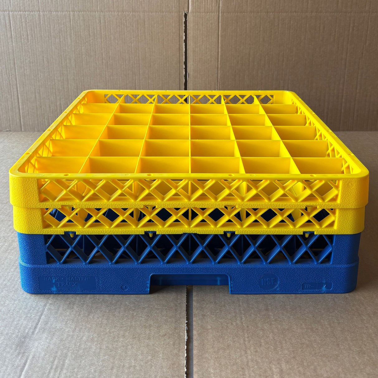 A USED - GREAT CONDITION Wineware Traex Rack Master Glass Washer Tray (500 x 500 x 160mm) for 36 glasses with 75mm cells sits on cardboard, featuring a grid pattern and stackable design for organizing glassware.
