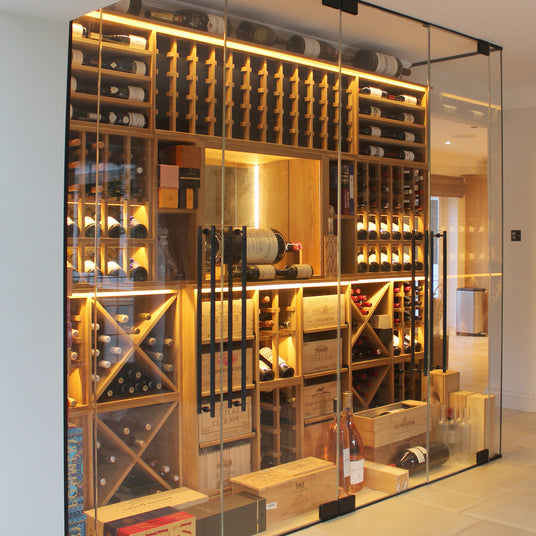 Modern wooden wine racking display with bottles, placed behind a glass fronted door and wall.