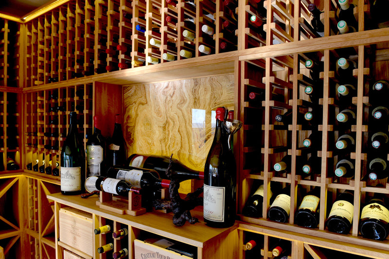 Wine cellar with bottles arranged in wooden shelves.