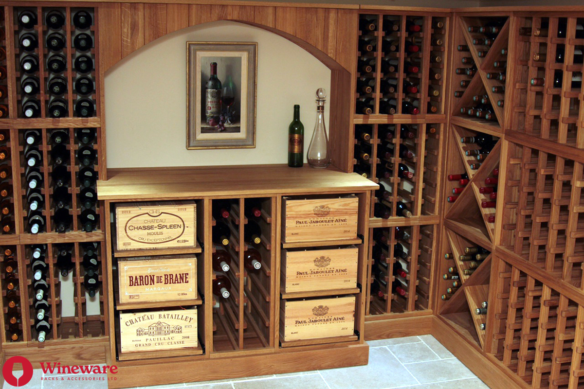 Wooden wine cellar with shelves and crates filled with wine bottles, featuring a framed picture on the wall.