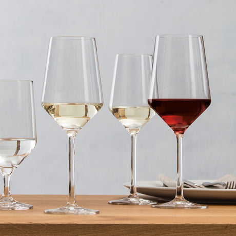 Four different shaped Schott Zwiesel wine and water glasses placed on a wooden table.