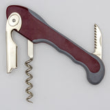 The Soft Touch 001 Single Lever Waiter's Friend Corkscrew by Soft Touch—a metal and plastic wine opener featuring a curved handle, spiral screw, single lever, and a small serrated knife for cutting foil—is displayed against a plain background.