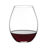 A Riedel O Range Stemless Old World Syrah Glass, from the set of two (0414/41) by Riedel, filled halfway with red wine, is positioned against a plain white background.