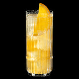 A tall, clear Riedel Restaurant Bar Rituals Highball Tumbler (321ml) from the 0421/04 set is filled with a fizzy, light-colored beverage, ice cubes, and garnished with an orange slice. Crafted from lead-free crystal by Riedel and sold as a set of 12, the glass stands out against a solid black background.