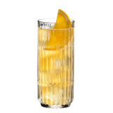 A Riedel Restaurant Bar Rituals Highball Tumbler (321ml) by Riedel, crafted from lead-free crystal, is filled with a fizzy yellow drink and garnished with a wedge of orange on the rim, set against a white background.
