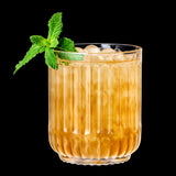 A glass of iced brown beverage garnished with a sprig of fresh mint, elegantly served in a lead-free crystal Riedel Restaurant Bar Rituals Double Rocks Tumbler (350ml), set against a striking black background.
