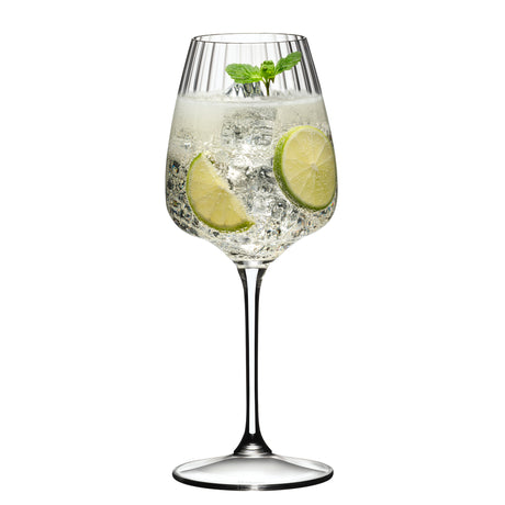 A Riedel Restaurant Grape Optical White Wine / Champagne / Spritz Glass (590ml) by Riedel, crafted from lead-free crystal, is filled with a sparkling beverage, ice cubes, two lime slices, and a sprig of mint, set against a white background.