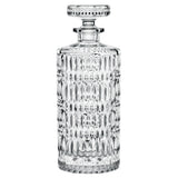 A clear, textured crystal glass decanter with a round stopper, featuring a geometric pattern and vertical ridges, is set against a white background. The Nachtmann Ethno Whisky Decanter & Two Glass Set by Nachtmann is an elegant addition that complements any whisky collection or your favorite tumblers.