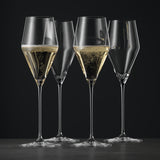 Four elegant Spiegelau Definition Universal Red & White Wine Glasses—crafted from fine crystal glass—stand gracefully, two filled with wine and catching the light, two empty, all set against a dark background on a smooth surface.