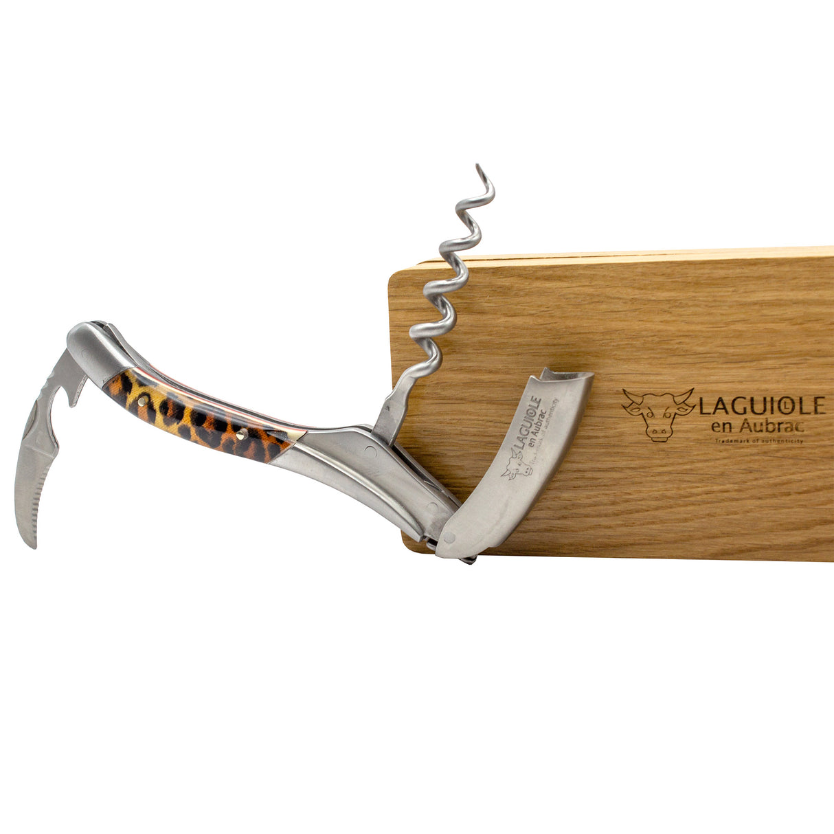 A Laguiole en Aubrac Sommelier Corkscrew with a leopard print handle is displayed open, leaning against a wooden box engraved with the Laguiole en Aubrac logo.