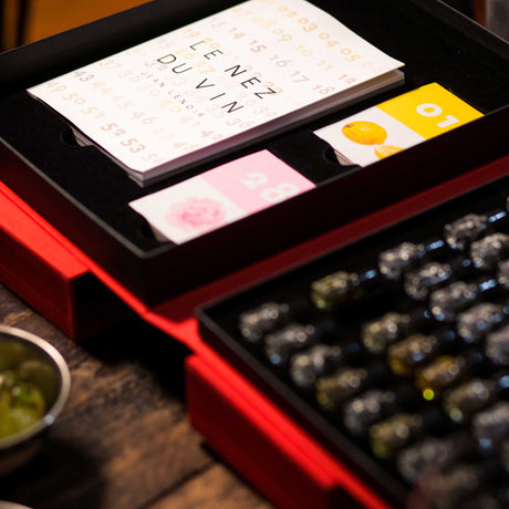 Red wine bottle set with cards and a small bowl on a wooden surface