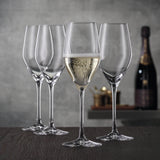 Four tall, slender Spiegelau Restaurant Authentis Champagne Glass 220ml - Set of 12 flutes stand on a wooden surface, with one glass filled with sparkling wine.
