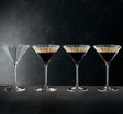 Four martini glasses with a layered drink on a dark background
