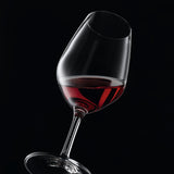 A clear, crystalline Spiegelau Expert Wine Tasting Glass (260ml) from the set of 6 is elegantly tilted with red wine against a solid black background, emphasizing the vibrant color of the wine and the refined silhouette of this premium glassware by Spiegelau.