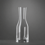 A clear, empty Spiegelau Ultra Wine / Water Carafe 500ml by Spiegelau stands upright on a dark surface against a plain gray background.