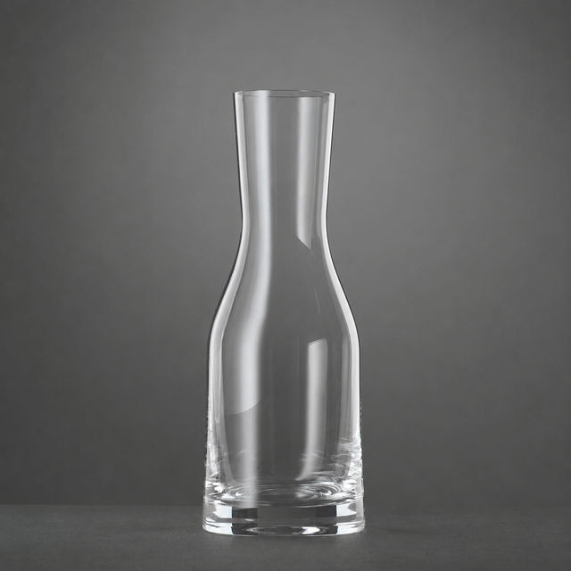 A clear, empty Spiegelau Ultra Wine / Water Carafe 500ml by Spiegelau stands upright on a dark surface against a plain gray background.