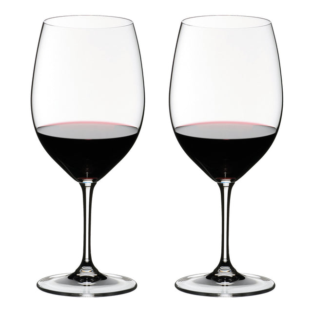 Two wine glasses filled with red wine on a white background