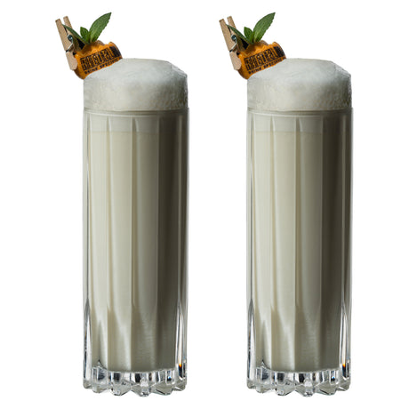 Two tall, faceted Riedel Bar Drink Specific Highball Tumbler - Set of 2 - 6417/03 glasses filled with a creamy, foamy cocktail, each garnished with a citrus slice, mint sprig, and wooden clothespin.