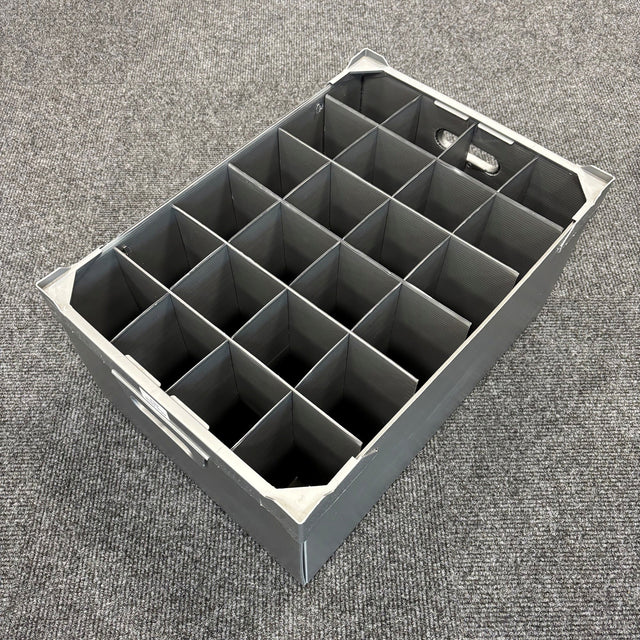 A USED - GREAT CONDITION Wine Glass Storage Box by Wineware, featuring 24 square compartments and measuring 230mm high, sits empty on a gray carpeted floor. The gray plastic box has handles on both ends and is ideal for securely storing wine glasses.