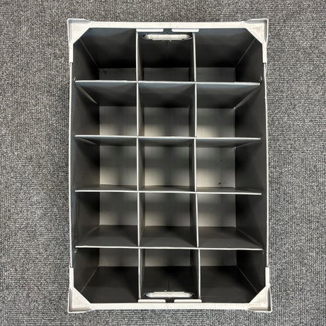 Top-down view of an empty Wineware USED - GREAT CONDITION Wine Glass Storage Box, featuring fifteen rectangular compartments arranged in a 3 by 5 grid, placed on a textured gray carpet. The dividers keep glassware separated, making this stackable 240mm high organizer ideal for safely storing and organizing delicate wine glasses.
