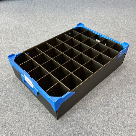 A USED - GREAT CONDITION black Wineware Wine Glass Storage Box with blue corner protectors, 35 square compartments (125mm high), sits on a grey carpet—perfect for storing glassware.