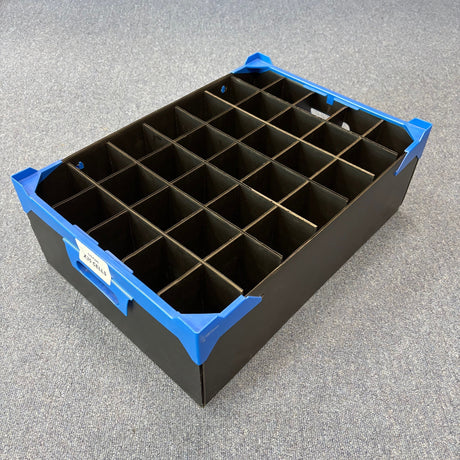 A USED - GREAT CONDITION Wineware Wine Glass Storage Box (165mm high, 35 cells) in black plastic with blue corner protectors is shown on a gray carpeted floor.