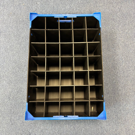 Top view of a blue USED - GREAT CONDITION Wineware Wine Glass Storage Box, 165mm high with 35 compartments, ideal for glassware storage, pictured on a gray carpeted floor.