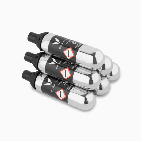 Six silver Coravin Pure Argon Gas Replacement Capsules stacked in a pile.