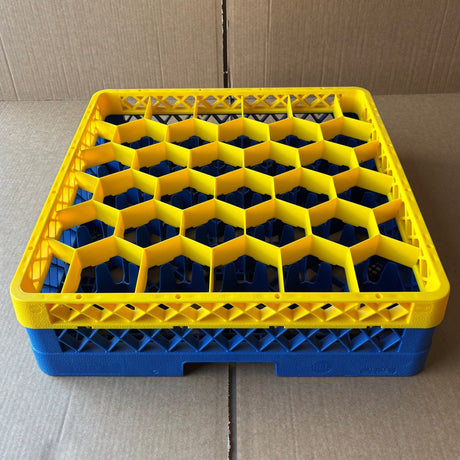 The USED - GREAT CONDITION Traex Rack Master Glass Washer Tray by Wineware (500x500x120mm, 30 glasses, 81mm cell) features a yellow honeycomb top and blue base, and is shown on a cardboard surface.