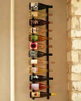 A VintageView Wall Mounted W Series 4 - 1220mm wine rack by VintageView displays up to thirty-six wine bottles horizontally, showcasing their colorful and unique labels against a white brick wall.