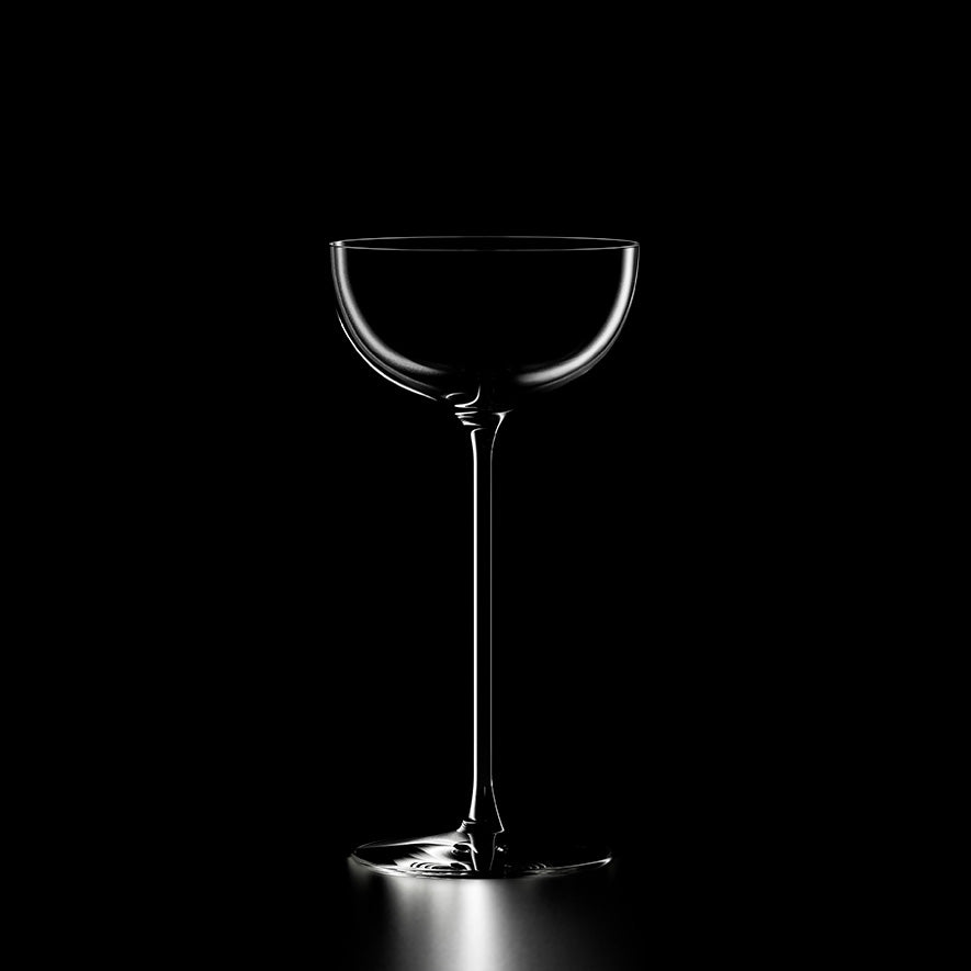 A set of six Lehmann Glass La Creative London Cocktail Coupes, each crafted from lead-free crystal and holding 200ml, is dramatically lit against a black background to emphasize their elegant silhouettes and refined contours.