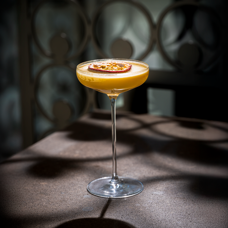A yellow cocktail in a Lehmann Glass La Creative Paris Cocktail Glass 200ml, garnished with a slice of passion fruit.