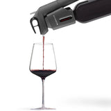 The Coravin Timeless Three+ Wine Preservation System by Coravin pours red wine from a bottle into a clear wine glass, shown against a white background.
