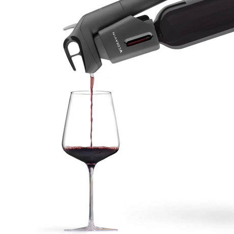The Coravin Timeless Three+ Wine Preservation System by Coravin pours red wine from a bottle into a clear wine glass, shown against a white background.